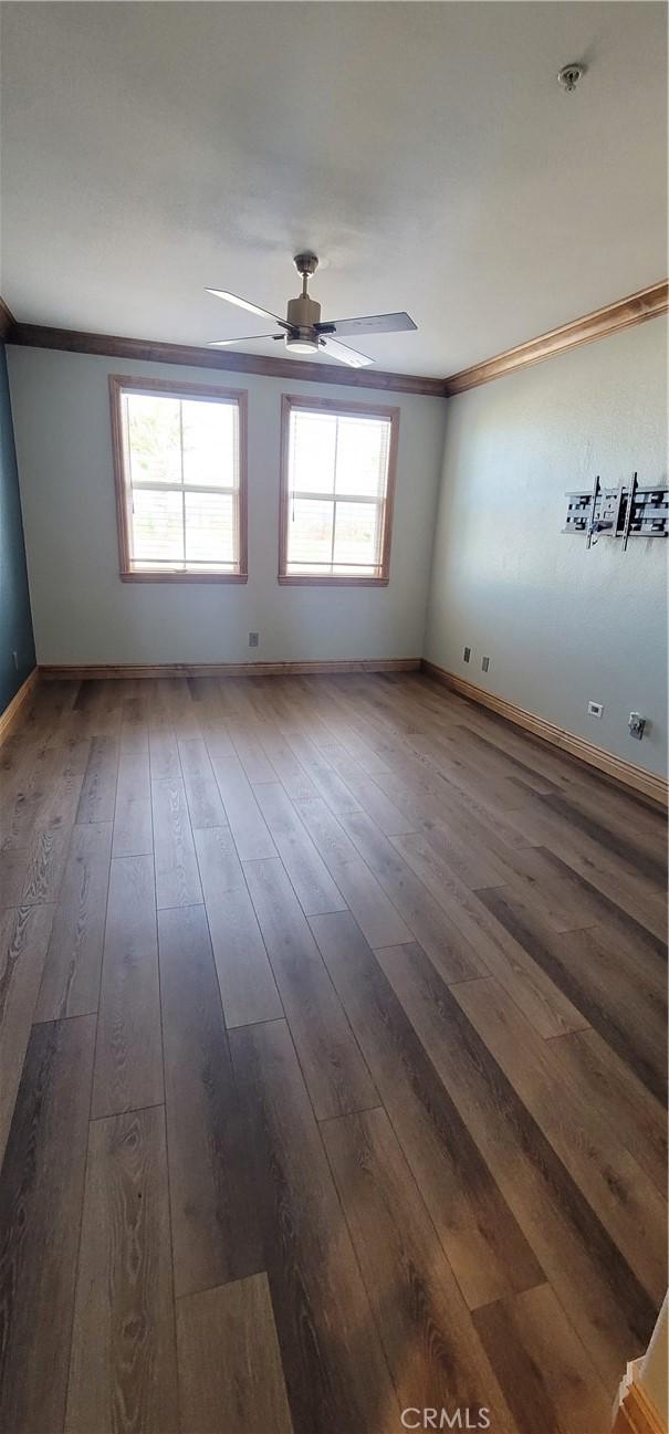 spare room with ceiling fan, ornamental molding, baseboards, and hardwood / wood-style flooring