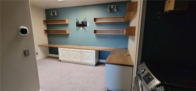 home office with baseboards, stacked washer / drying machine, and light carpet