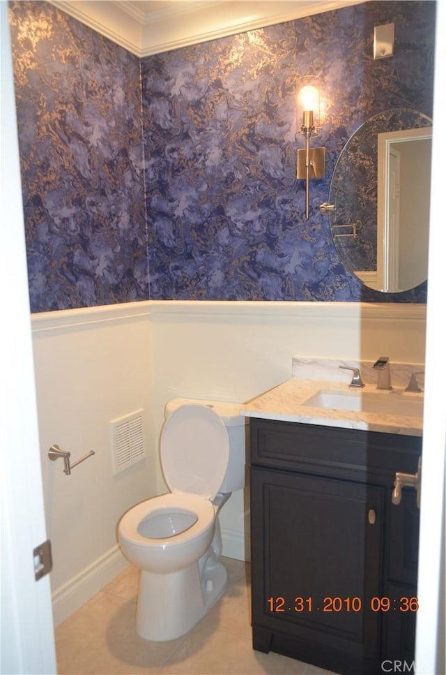 half bathroom with visible vents, crown molding, vanity, toilet, and a wainscoted wall