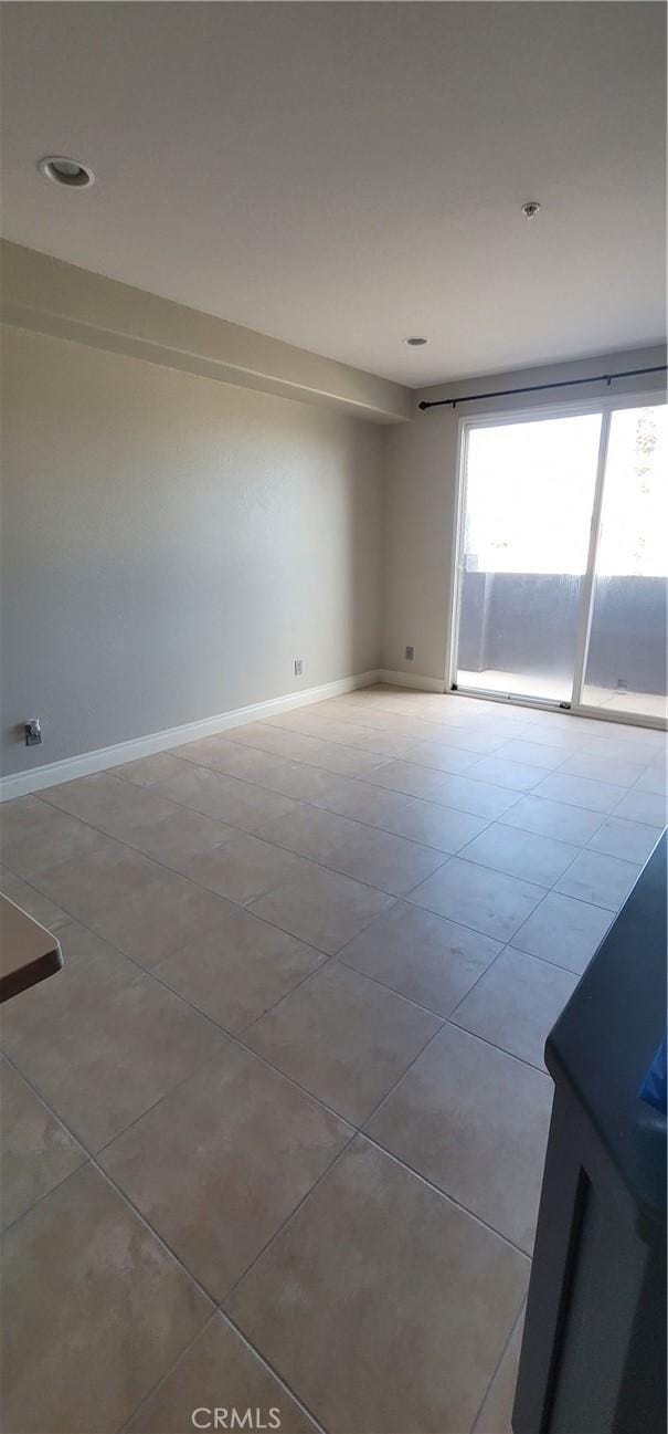 tiled empty room featuring baseboards