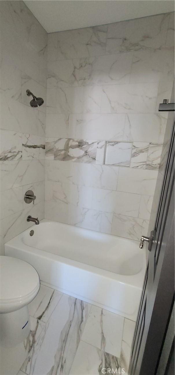 bathroom featuring toilet, shower / washtub combination, and marble finish floor