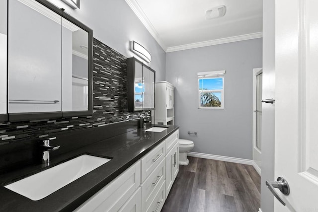 bathroom with crown molding, a sink, backsplash, and toilet
