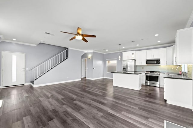 kitchen featuring a sink, dark countertops, stainless steel appliances, and open floor plan