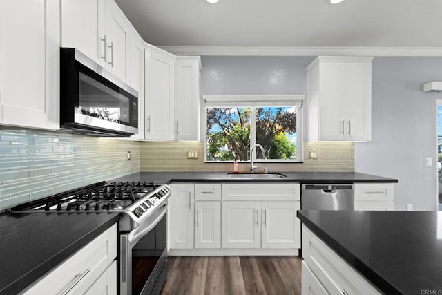 kitchen featuring white cabinets, dark countertops, appliances with stainless steel finishes, and a sink