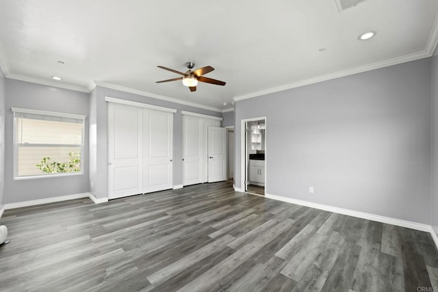 unfurnished bedroom with wood finished floors, recessed lighting, baseboards, and two closets