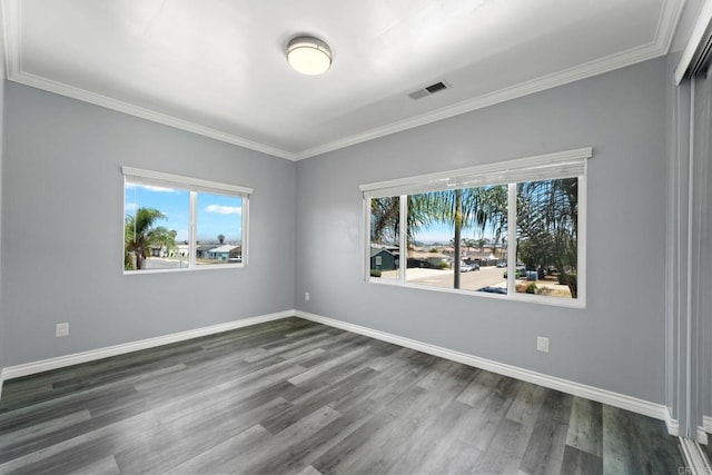 spare room featuring baseboards, ornamental molding, dark wood-style floors, and visible vents