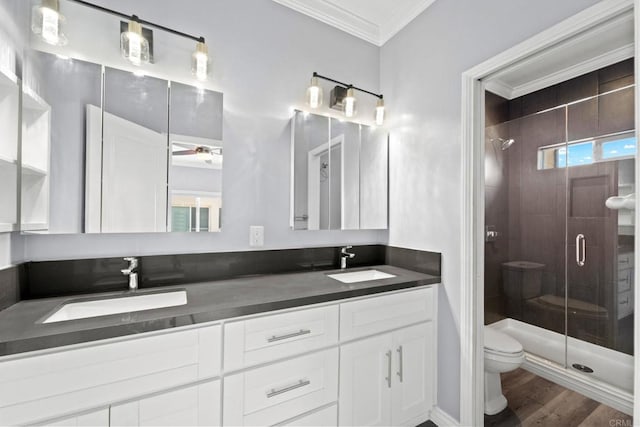 bathroom featuring a shower stall, toilet, ornamental molding, and a sink