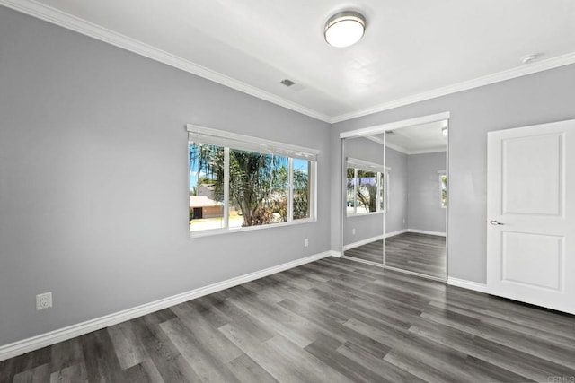 spare room featuring visible vents, ornamental molding, baseboards, and wood finished floors