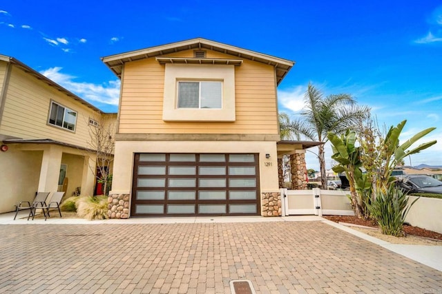 view of front of house with a gate, an attached garage, decorative driveway, and stone siding