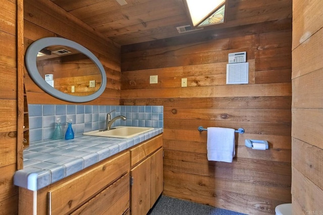 bathroom with vanity, wood walls, wooden ceiling, backsplash, and visible vents