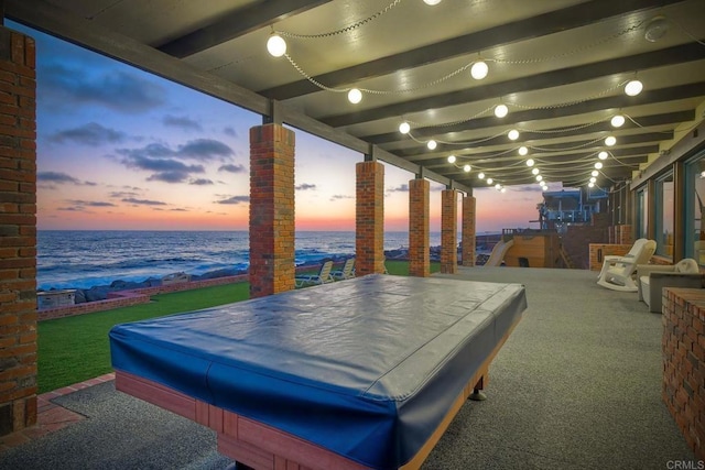 patio terrace at dusk featuring a water view
