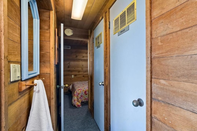 hallway featuring wood walls, carpet, and wooden ceiling