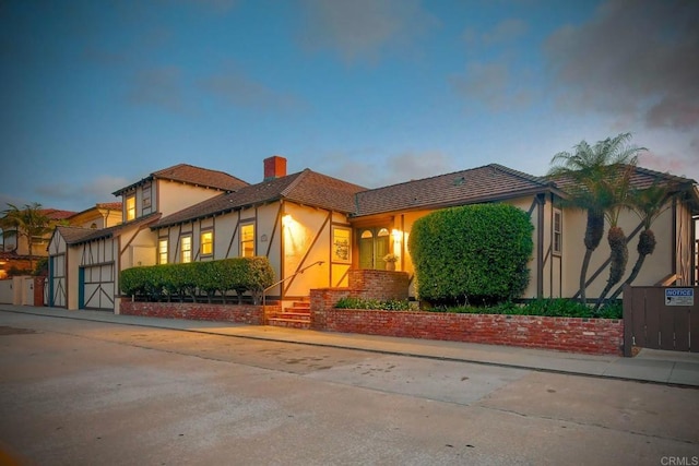 view of front of property with an attached garage, stucco siding, driveway, and a chimney