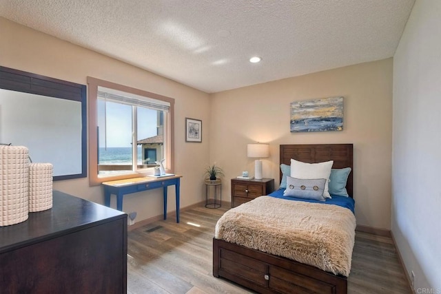 bedroom featuring a textured ceiling, baseboards, recessed lighting, and light wood-style flooring