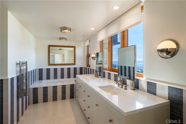 bathroom with double vanity, tiled bath, recessed lighting, and a sink