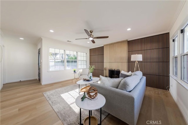 living area featuring ornamental molding, baseboards, light wood-style floors, ceiling fan, and recessed lighting