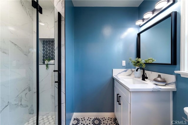 full bath featuring baseboards, a marble finish shower, and vanity