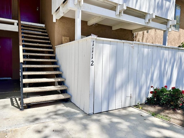 entry to storm shelter featuring fence and stairs
