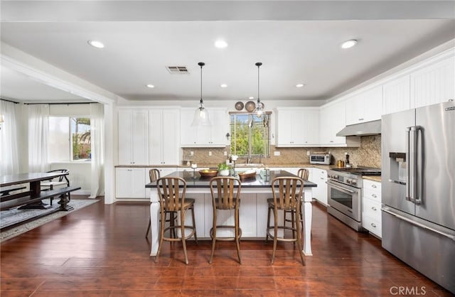 13216 Finish Draft Ct, Eastvale, CA 92880 - kitchen featuring high quality appliances, under cabinet range hood, white cabinets, decorative backsplash, and recessed lighting