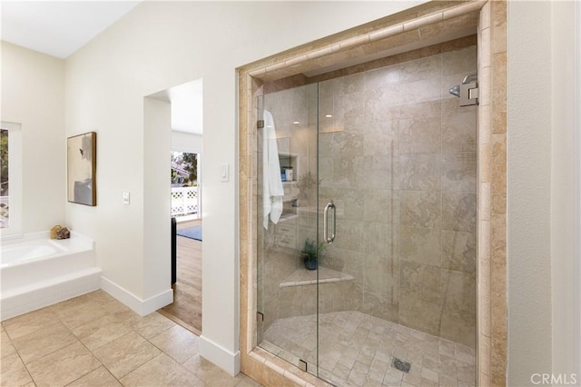 full bathroom with baseboards, a garden tub, and a stall shower