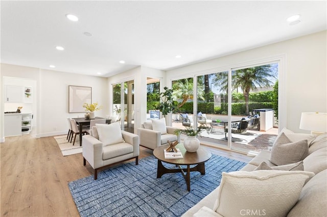 living area featuring recessed lighting, baseboards, and light wood-type flooring