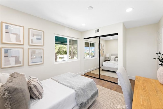 bedroom featuring visible vents, a closet, wood finished floors, baseboards, and recessed lighting