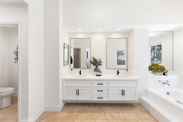 full bathroom with double vanity, a sink, a bath, and toilet