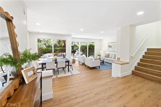 living room with recessed lighting, light wood finished floors, and stairway
