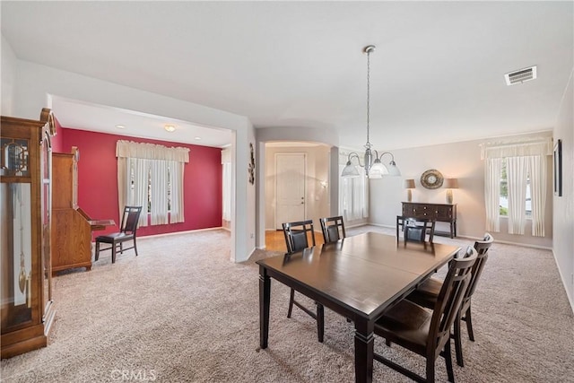 dining space featuring visible vents, arched walkways, baseboards, a notable chandelier, and carpet