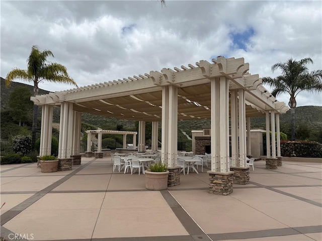 view of property's community with a pergola, outdoor dining space, and a patio