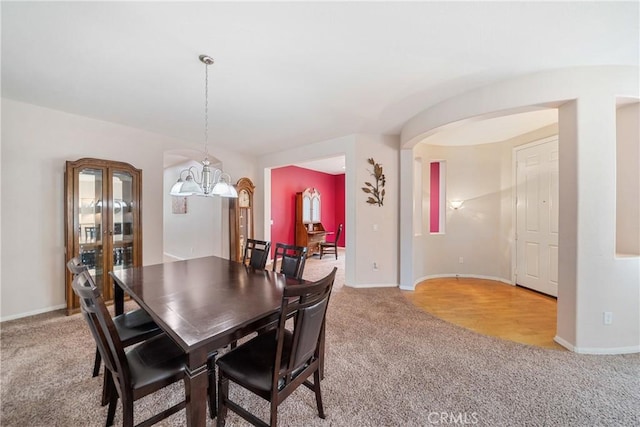dining space featuring baseboards, light colored carpet, and an inviting chandelier