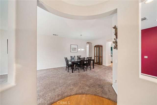 carpeted dining space featuring arched walkways, baseboards, and visible vents