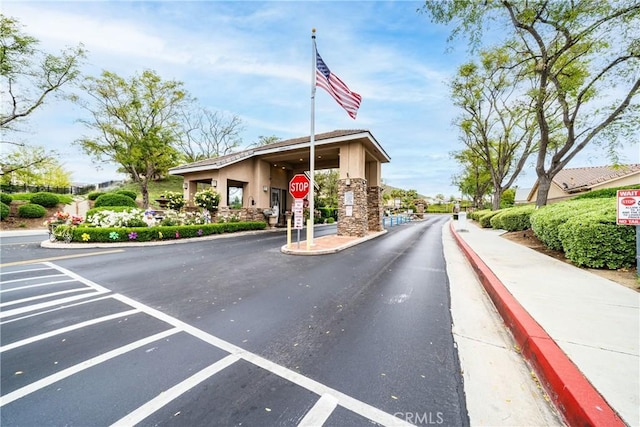 view of street with a gated entry, traffic signs, and curbs