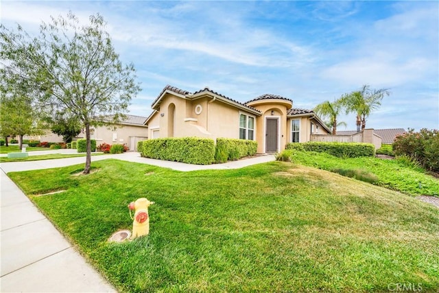 mediterranean / spanish home with a tiled roof, driveway, a front lawn, an attached garage, and stucco siding