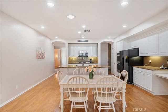 dining area with visible vents, arched walkways, light wood-style flooring, and recessed lighting