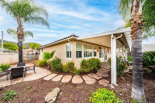view of property exterior with a patio, fence, and stucco siding