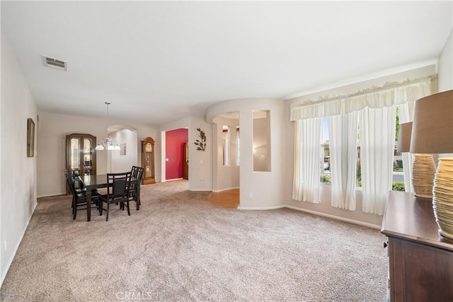 dining area with visible vents, arched walkways, baseboards, an inviting chandelier, and carpet flooring