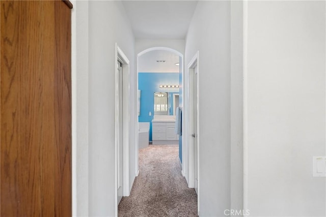 hall with arched walkways and carpet