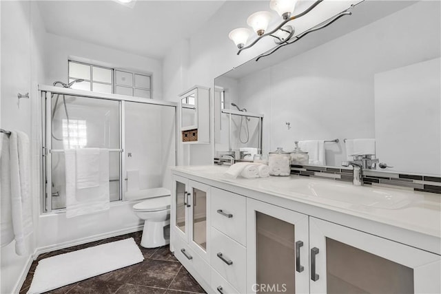 full bath featuring a sink, double vanity, toilet, and shower / bath combination with glass door