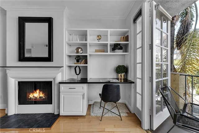 office featuring ornamental molding, light wood-style flooring, built in desk, and a wealth of natural light