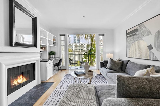 living area with crown molding, a fireplace with flush hearth, and light wood-style flooring