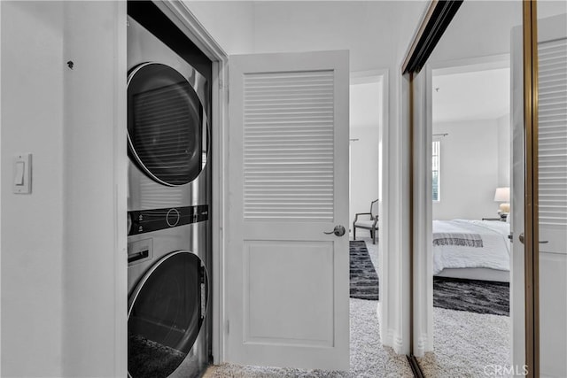 washroom with carpet floors, stacked washer and dryer, and laundry area