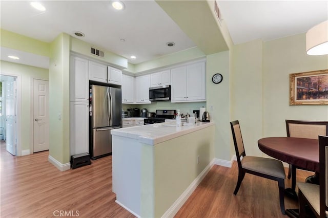 13435 Cascade Ct, Cerritos, CA 90703 - kitchen featuring a peninsula, appliances with stainless steel finishes, light wood finished floors, and white cabinets