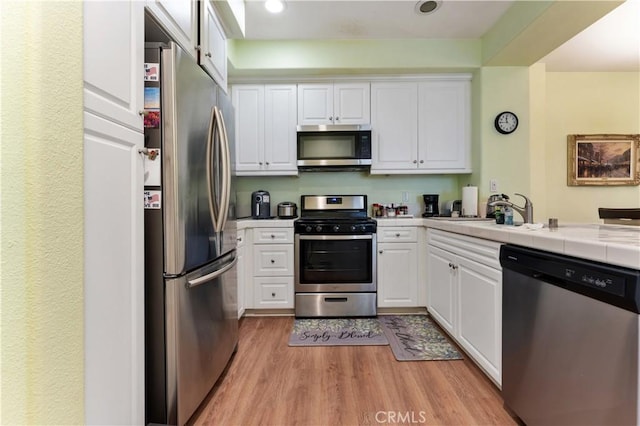 13435 Cascade Ct, Cerritos, CA 90703 - kitchen featuring a sink, white cabinetry, tile counters, and appliances with stainless steel finishes
