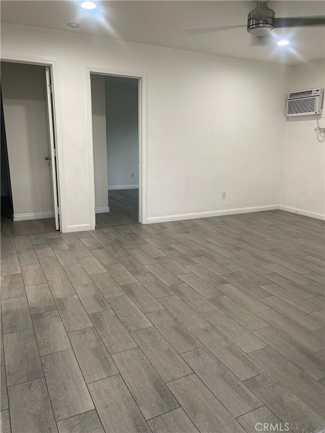 interior space with wood finished floors, baseboards, a wall mounted air conditioner, recessed lighting, and a ceiling fan
