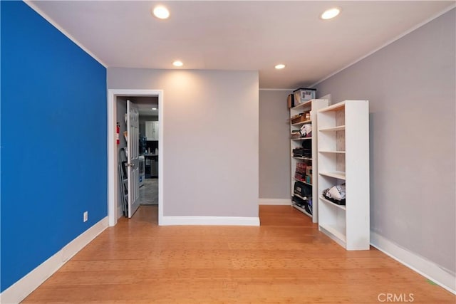 spare room featuring crown molding, recessed lighting, light wood finished floors, and baseboards