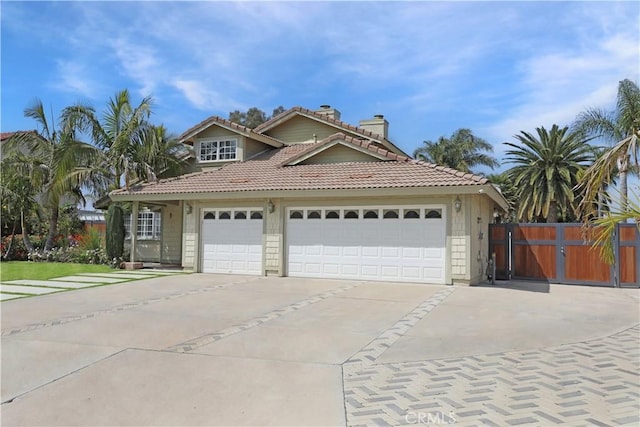 view of front of property featuring a chimney, driveway, fence, an attached garage, and a tile roof