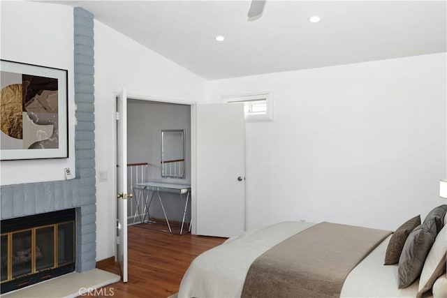 bedroom featuring vaulted ceiling, wood finished floors, a brick fireplace, and recessed lighting