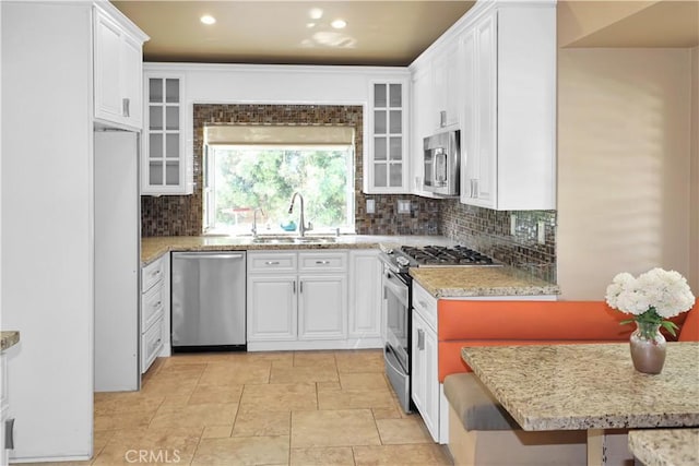 kitchen featuring a sink, stainless steel appliances, decorative backsplash, and white cabinets