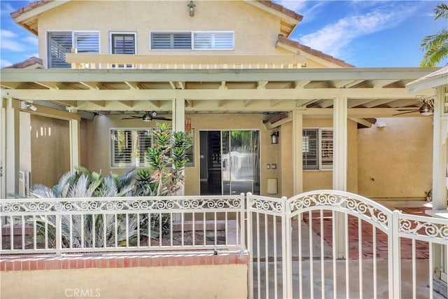 view of exterior entry featuring stucco siding, a tile roof, fence, and a gate